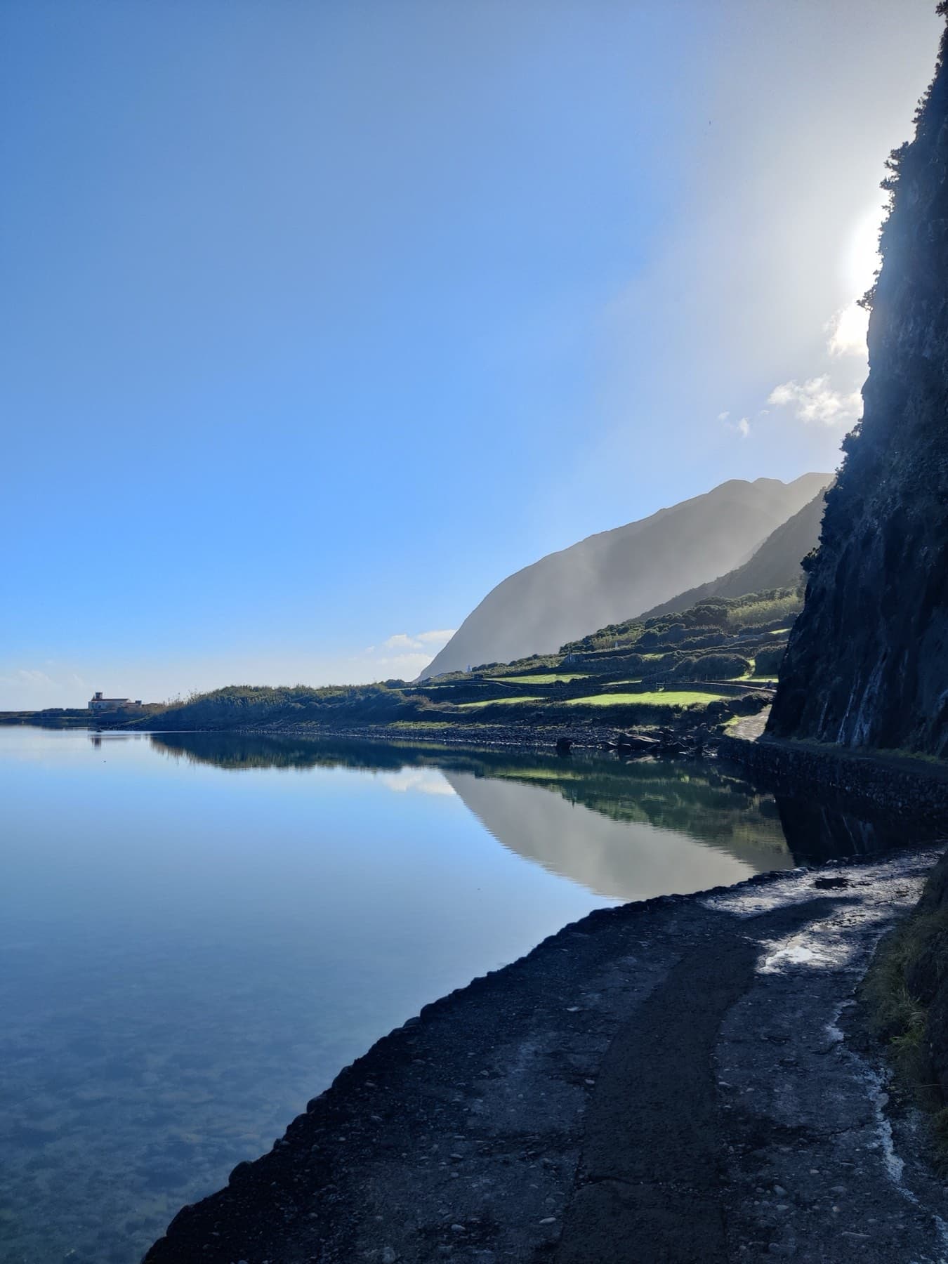 A path along still water at the foot of the cliffs
