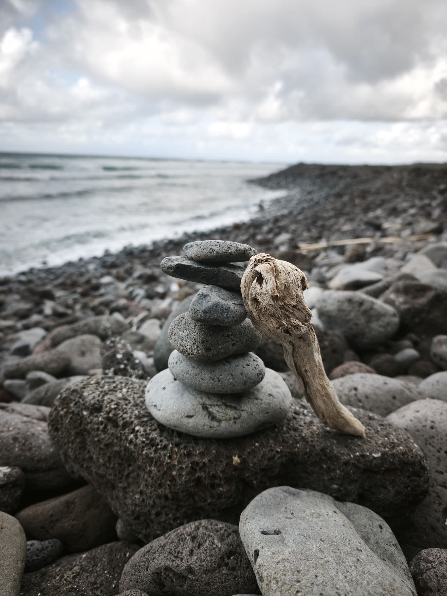 A cairn of volcanic stones and driftwood on the shore of São Jorge